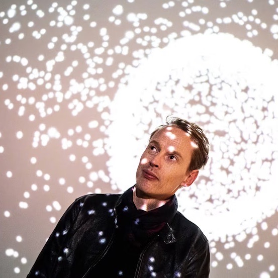Artist Daan Roosegaarde surrounded by his floating bioluminescent artwork, SPARK